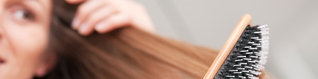 Mulher escovando seu cabelo forte e saudável depois de colocar as dicas que encontrou sobre o que é bom para caspa em prática