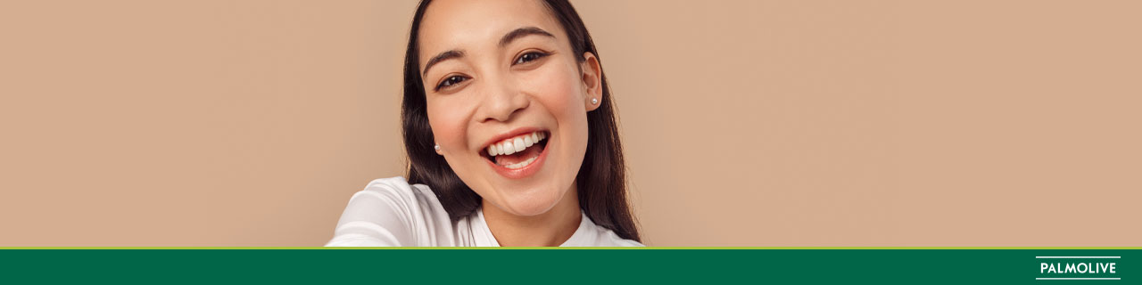 Mulher de cabelos longos e brilhosos sorrindo após fazer umectação com óleo capilar