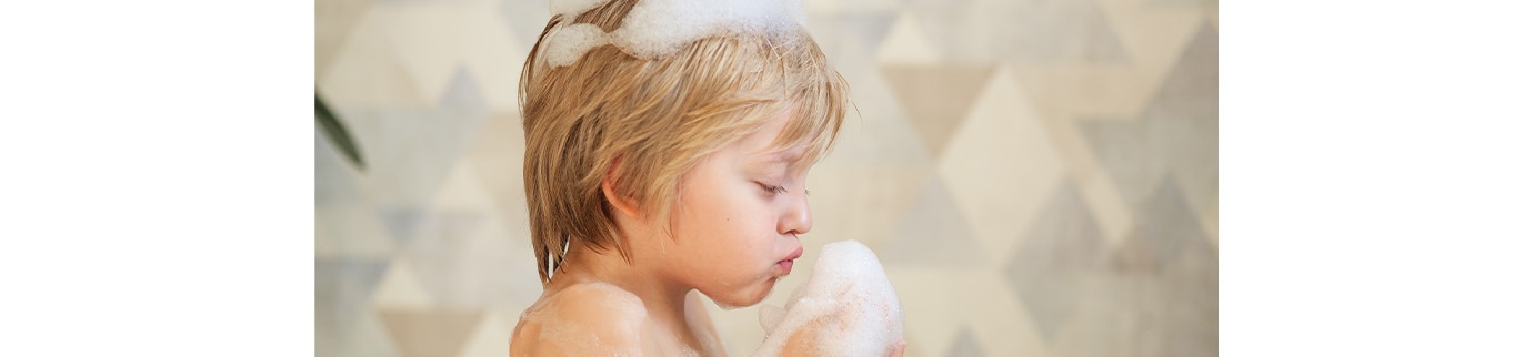 Menina sorrindo com condicionador infantil em seus cabelos