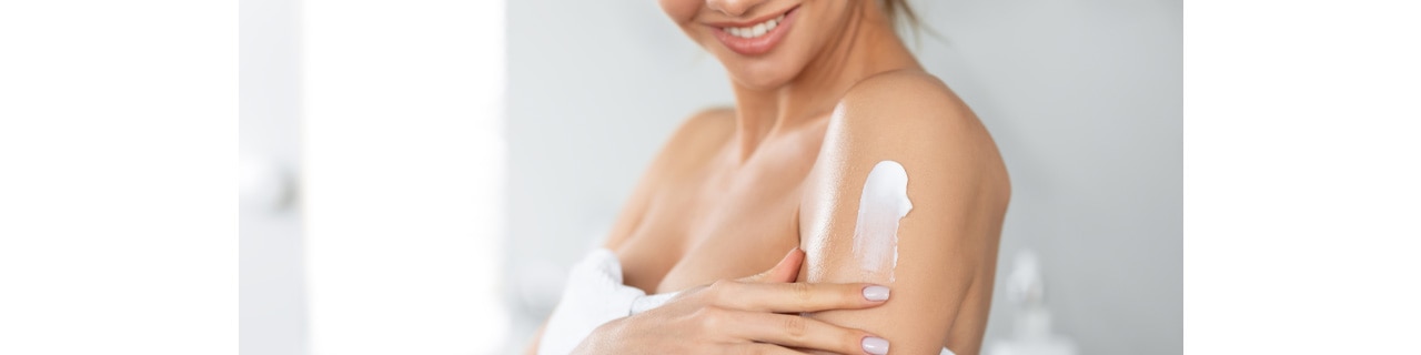 Mulher passando creme corporal no braço, colocando em prática as dicas deste artigo sobre hidratação para pele seca.