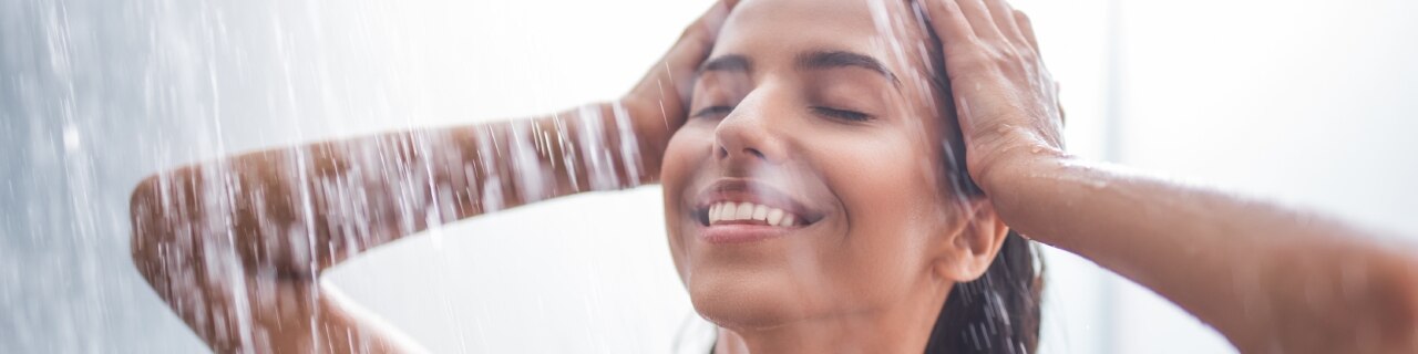 Mulher no chuveiro com expressão de relaxamento enquanto aproveita os benefícios do banho premium.