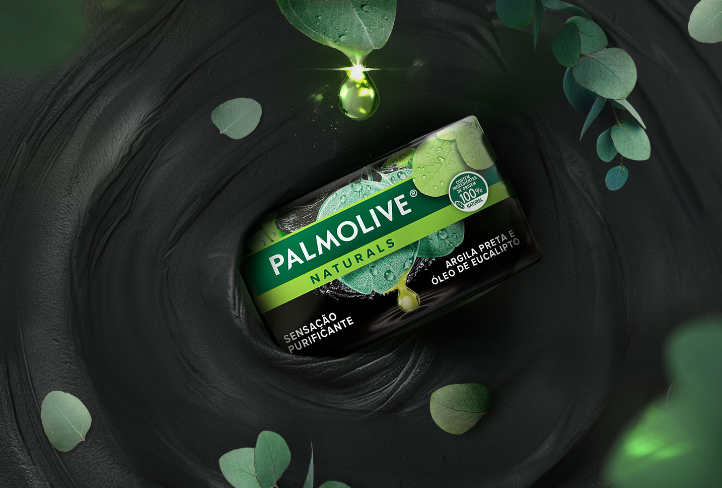 Embalagem do sabonete Palmolive Naturals Argila Preta e Óleo de Eucalipto, cercada por folhas de eucalipto com gotas de água, destacando a fragrância natural e os ingredientes purificantes.