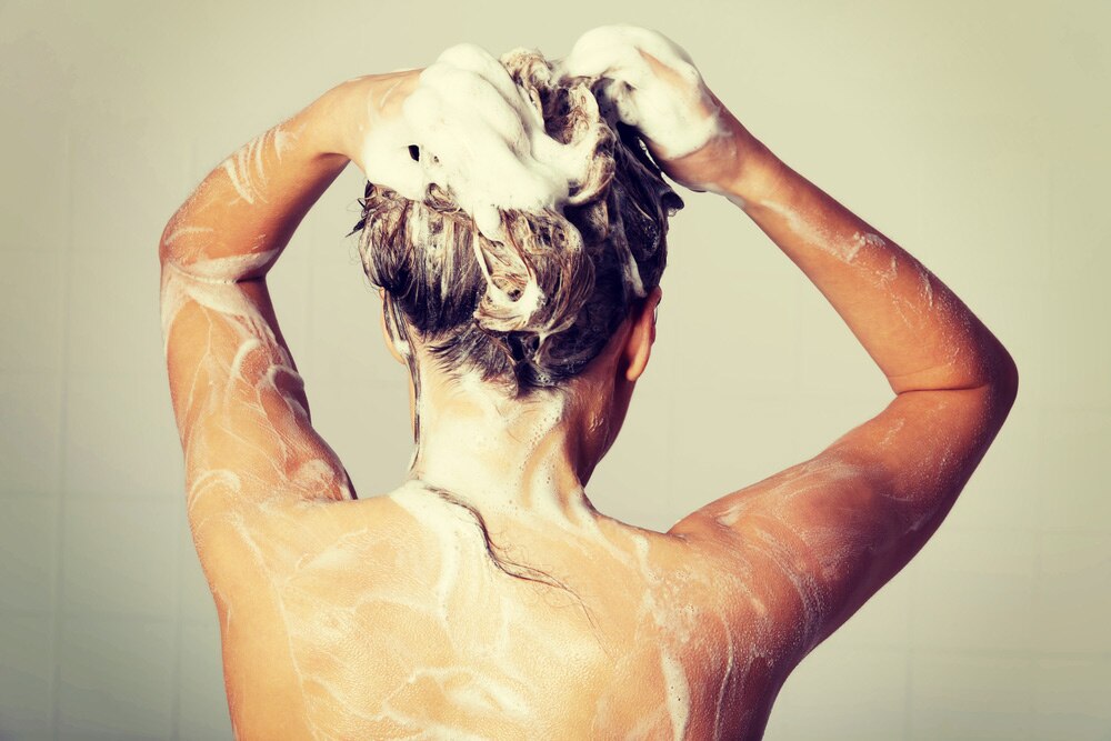 Mujer lavándose el cabello en la ducha Mujer lavándose el cabello en la ducha